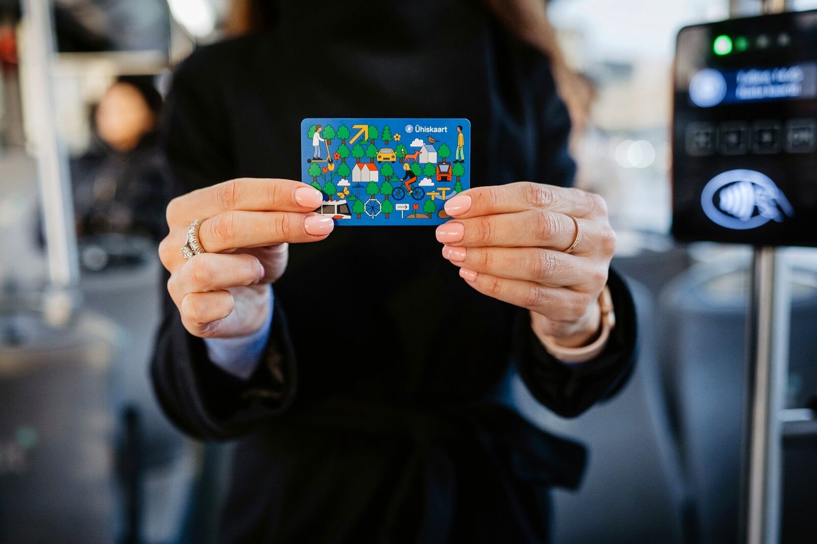A blue Tallinn Ühiskaart held in front of a validator