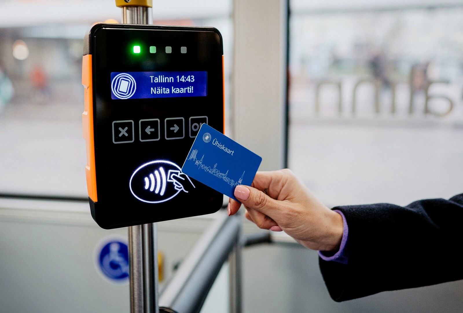 A blue Ühiskaart being validated on a Tallinn tram validator — the screen reads
